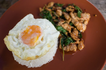Rice topped with stir-fried pork and basil served with fried egg (Blurred background)