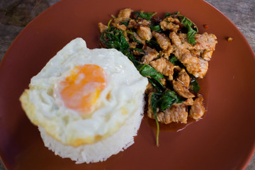 Rice topped with stir-fried pork and basil served with fried egg (Blurred fore ground)