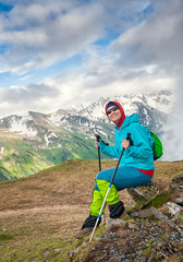 Young happy woman hiker sitting on the top of mountain