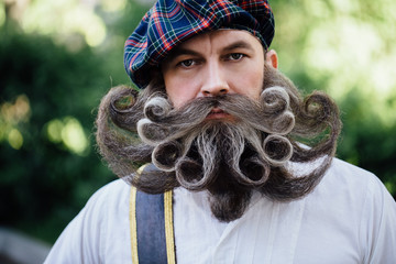 Handsome portrait of a brave Scot with a amazing beard and mustache curls in the Hungarian style. - obrazy, fototapety, plakaty