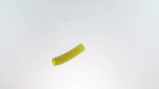 macaroni pasta splash falling into boiled water, shot in slow motion on white background, italian nutrition and health care concept