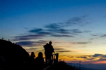 Fototapeta na wymiar Silhouette of woman standing on the mountain against vivid sunset sky,located phu chi dao ,thailand.