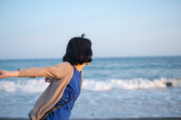 Fototapeta na wymiar 海に向かって石を投げる女性