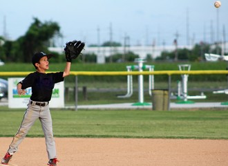 Boy with glove up to catch incoming baseball