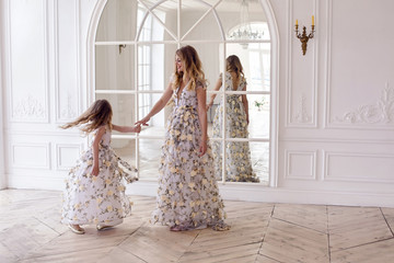 mother and daughter dancing in the mirror in the same dress in a big white room
