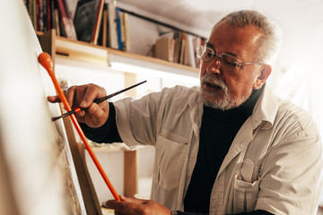 Old man artist painting oils in his studio. - Powered by Adobe