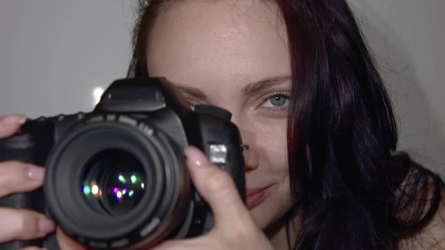 Young photographer works in the Studio. A woman takes the Picture on the camera. The camera is in the process of close-up shooting. Shutter release in slow motion.