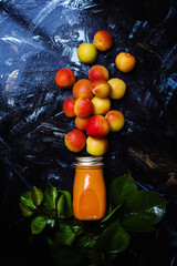 Freshly squeezed apricot juice in glass bottle, black food background, top view