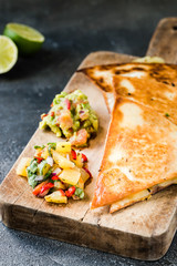Grilled quesadillas (tortillas) with salsa, guacamole. Dark background.