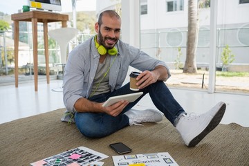 Portrait of designer holding disposable cup and tablet computer