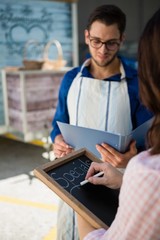 Naklejka premium Woman writing menu while coworker reading document