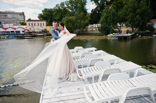 Beautiful couple walking on a wharf on a sunny wedding day.