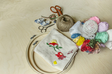 Needles, scissors, colored thread and frame necessary tools for decorative embroidery


