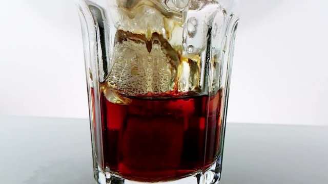 pouring of fresh coke in the drink glass on white background, shot slow motion, fun and summer time concept