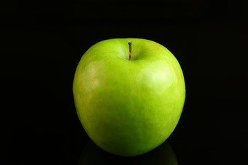A fresh Granny Smith apple on a black background.