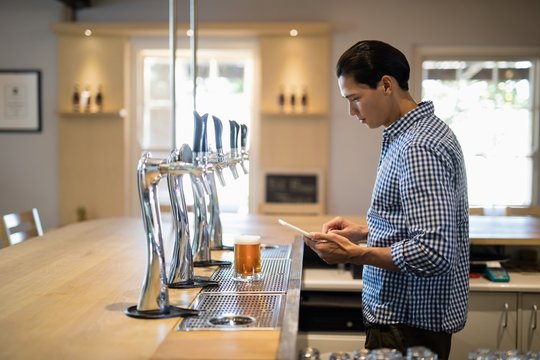 Bar tender using digital tablet at counter