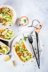 Healthy food snack. Tortillas taco with grilled chicken, avocado, fresh salsa, lettuce, lime. With yogurt & parsley sauce. On light gray stone marble table, marble plate. Copy space top view