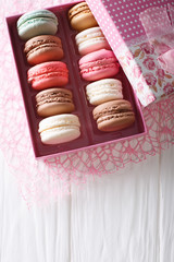 Beautiful food: French macaroons in a gift box close-up on a table. Vertical top view