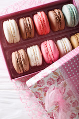 Festive macaroons in a beautiful gift box close-up on a table. Vertical top view