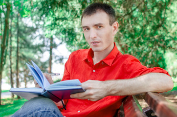 student boy posing looking at you sitting on the grass in a park