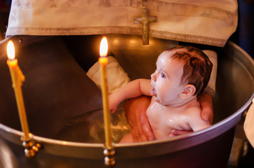 Baptism of a child in the Orthodox Church. Baby christening. Newborn is in the church font.