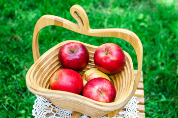 Fresh apples in a wooden basket on green grass. Apple.