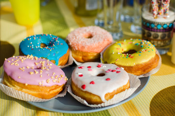 Assorted donuts in the glaze on the festive table. Sweet pastries.