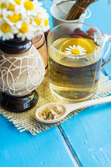 cup of herbal chamomile tea with fresh daisy flowers on blue wooden background. doctor treatment and prevention of immune concept, medicine - folk, alternative, complementary, traditional medicine 
