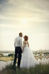 Elegant gentle stylish groom and bride near river or lake. Wedding couple in love