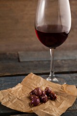 Close up of black olives on paper by red wine