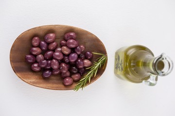 Directly above shot of brown olives in plate by oil in jar