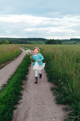 A cheerful child runs with a bouquet of daisies in boots