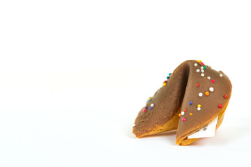 Close up of a chocolate covered fortune cookie with sprinkles isolated on white with a shallow depth of field and copy space