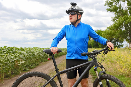 cyclist with Bicycle standing on field path.