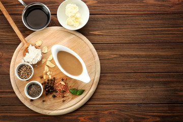 Tasty turkey gravy in sauce boat and spices on wooden board
