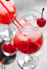 Tequila cocktail with ice cubes and cherry on table