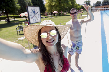 Fototapeta premium Young loving couple beside the pool takes a selfie