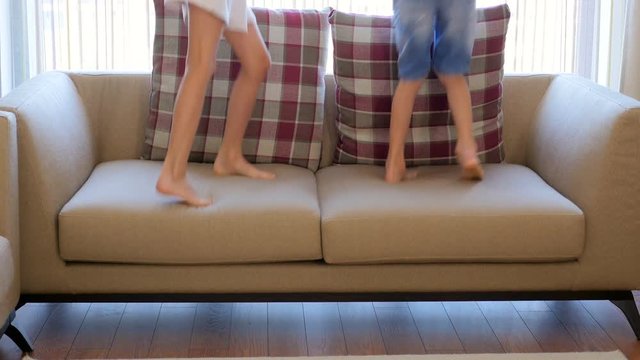 The children are having fun. A boy and a girl are jumping on the couch. The children are dancing. The children are jumping. Happy children.