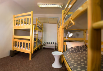 Interior of the hostel bedroom. Hostel with wooden bunk beds - obrazy, fototapety, plakaty