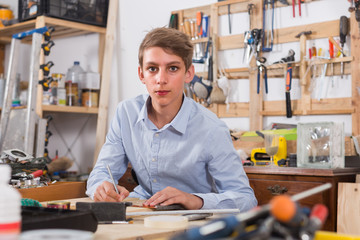 teenager  smiling and working with wood in the workshop