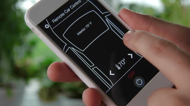 Man remotely changes temperature in his car Car remote control using smartphone application fictional interface.