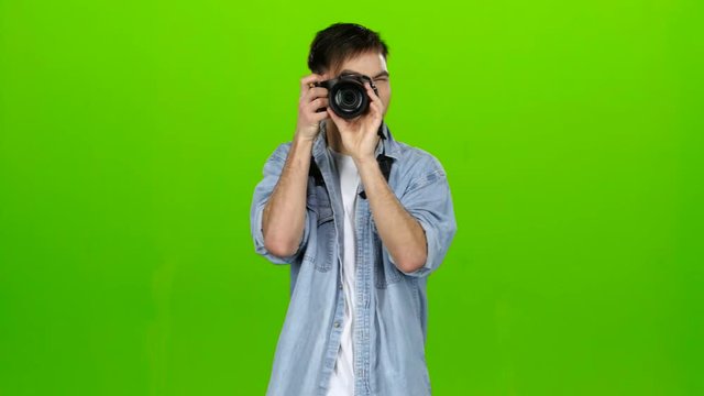 Man takes pictures of the landscapes on the professional camera. Green screen