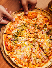 Hot pizza slice with melting cheese on a rustic wooden table.