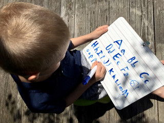 Boy writing ABC's outside