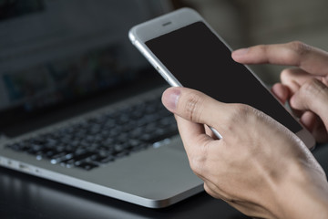 Man using smartphone Black screen with laptop background