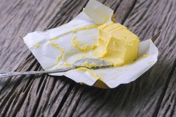 Butter and spoon on wooden background.