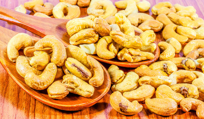 Roasted cashew nuts on a wooden spoon.Roasted salted cashew nuts on white background. Healthy food, cashews rich in heart friendly fatty acids. Cashew nuts as food background.