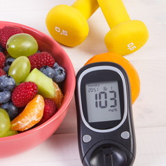 Fruit salad, glucose meter and dumbbells, diabetes, healthy food and nutrition concept
