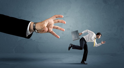Business man running away from a huge hand concept