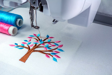Close up picture workspace of  embroidery machine show embroider tree design theme. And two thraed...